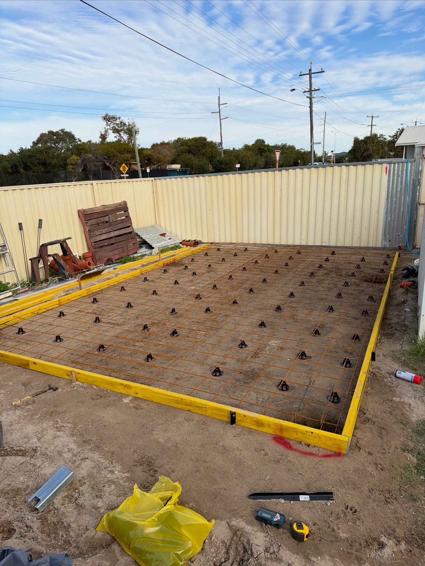 Padbury shed pad before the pour: yellow formwork and steel mesh on bar chairs over the compacted pad